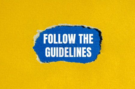 Suivez les lignes directrices mots écrits sur du papier jaune déchiré avec fond bleu. Conceptuel suivre le symbole des lignes directrices. Espace de copie.