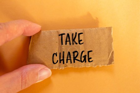 Take charge words written on ripped cardbaord paper with orange background. Conceptual take charge symbol. Copy space.