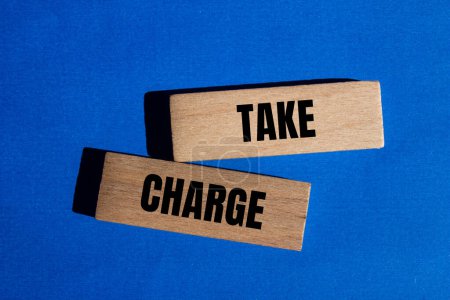 Take charge words written on wooden blocks with blue background. Conceptual take charge symbol. Copy space.