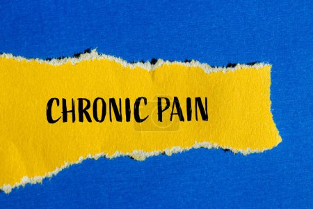 Chronic pain words written on ripped yellow paper with blue background. Conceptual chronic pain symbol. Copy space.