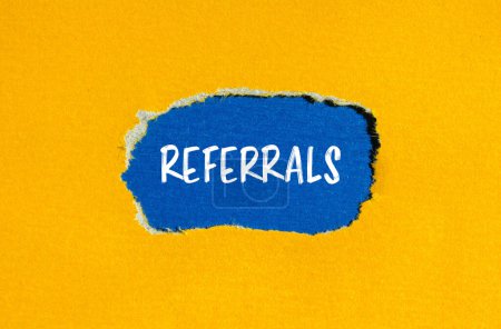 Photo for Referrals word written on ripped yellow paper with blue background. Conceptual referrals symbol. Copy space. - Royalty Free Image