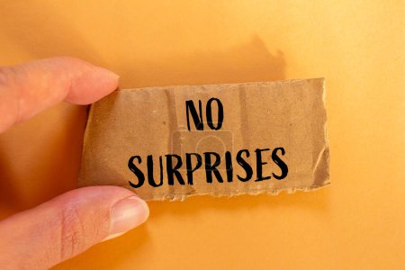 No surprises words written on ripped cardboard paper with orange background. Conceptual no surprises symbol. Copy space.
