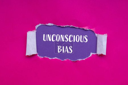 Unconscious bias words written on ripped pink paper with purple background. Conceptual unconscious bias symbol. Copy space.