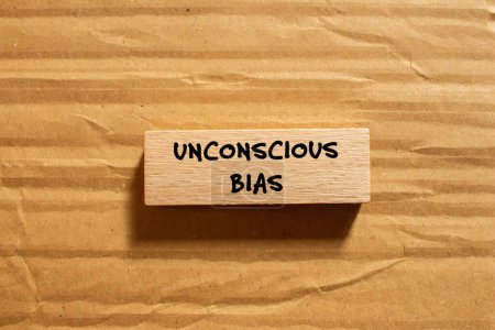 Unconscious bias words written on wooden block with cardboard background. Conceptual unconscious bias symbol. Copy space.