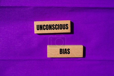 Unconscious bias words written on wooden blocks with purple background. Conceptual unconscious bias symbol. Copy space.