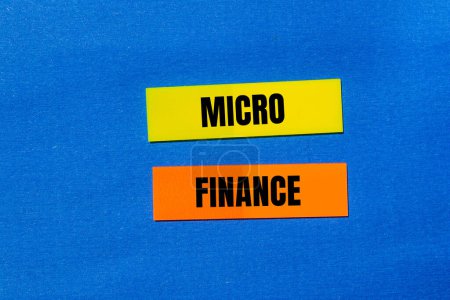 Palabras de micro finanzas escritas en pegatinas de papel de colores con fondo azul. Símbolo conceptual del negocio de microfinanzas. Copiar espacio.