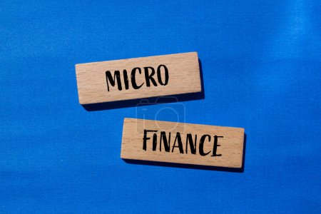 Palabras microfinancieras escritas en bloques de madera con fondo azul. Símbolo conceptual del negocio de microfinanzas. Copiar espacio.