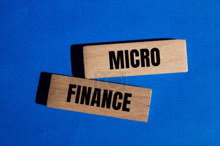 Palabras microfinancieras escritas en bloques de madera con fondo azul. Símbolo conceptual de microfinanzas. Copiar espacio.