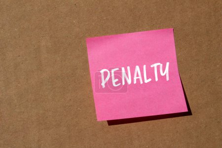 Penalty word written on pink paper sticker with brown background. Conceptual penalty symbol. Copy space.