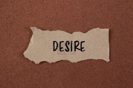 Desire word written on ripped paper piece with brown background