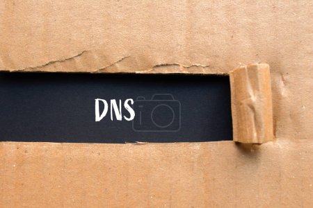 Mot DNS écrit sur du papier cartonné déchiré avec fond noir. Symbole DNS conceptuel. Espace de copie.