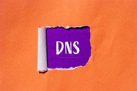 Mot DNS écrit sur papier orange déchiré avec fond violet. Symbole DNS conceptuel. Espace de copie.