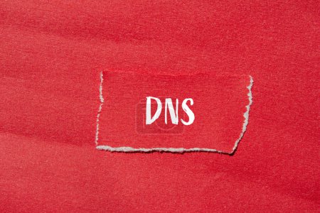 Mot DNS écrit sur papier rouge déchiré avec fond rouge. Symbole DNS conceptuel. Espace de copie.