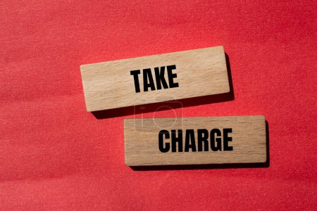 Take charge words written on wooden blocks with red background. Conceptual take charge symbol. Copy space.