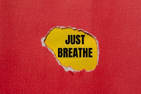 Just breathe words written on ripped red paper with yellow background. Conceptual just breathe symbol. Copy space.