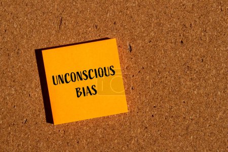 Unconscious bias words written on orange paper sticker with brown background. Conceptual unconscious bias symbol. Copy space.