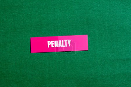 Mot de pénalité écrit sur autocollant en papier rose avec fond vert. Symbole conceptuel du mot pénalité. Espace de copie.