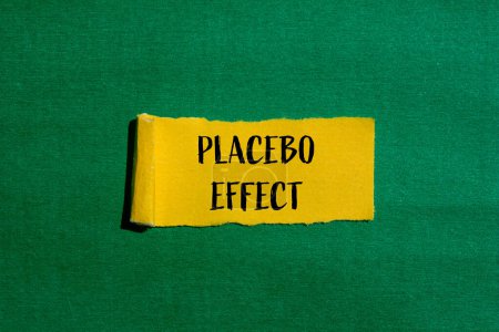 Mots à effet placebo écrits sur papier jaune déchiré avec fond vert. Symbole conceptuel de l'effet placebo. Espace de copie.
