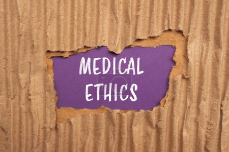 Mots d'éthique médicale écrits sur du papier cartonné déchiré avec fond violet. Symbole d'éthique médicale conceptuelle. Espace de copie.