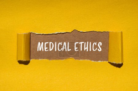 Mots d'éthique médicale écrits sur papier jaune déchiré avec fond brun. Symbole d'éthique médicale conceptuelle. Espace de copie.