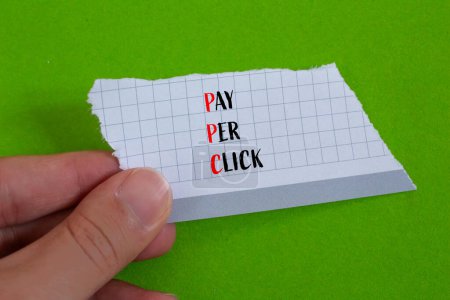 Payez par clic les mots écrits sur du papier déchiré avec un fond vert. PPC conceptuel payer par clic symbole. Espace de copie.