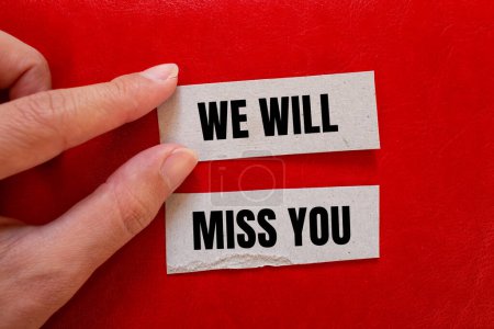 We will miss you words written on paper pieces with red background. Conceptual we will miss you symbol. Copy space.