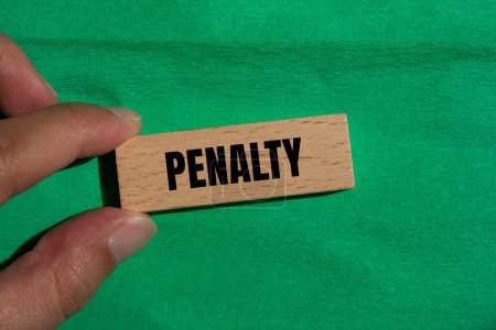 Penalty word written on wooden block with green background. Conceptual penalty symbol. Copy space.
