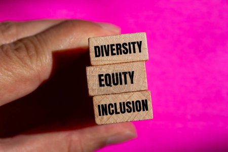 Diversity, equity and inclusion words written on wooden block with pink background. Conceptual diversity, equity and inclusion DEI symbol. Copy space.