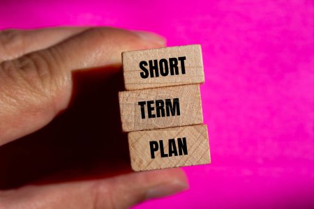 Short term plan words written on wooden blocks with pink background. Conceptual short term plan symbol. Copy space.