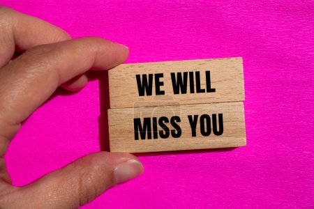 Wir werden dich vermissen, Worte, die auf Holzklötzen mit rosa Hintergrund geschrieben sind. Konzeptionell werden wir dich vermissen. Kopierraum.