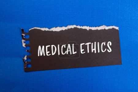 Message d'éthique médicale écrit sur papier noir déchiré avec fond bleu. Symbole d'éthique médicale conceptuelle. Espace de copie.