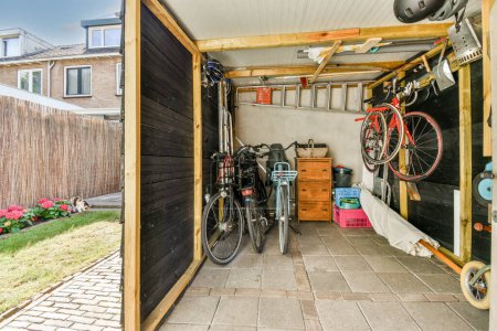 Foto de Amplio garaje con bicicletas y muebles de almacenamiento cerca de un pequeño jardín - Imagen libre de derechos