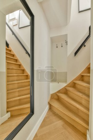 Foto de Interior del pasillo estrecho con radiador colgado en la pared contra la escalera a la luz del día - Imagen libre de derechos