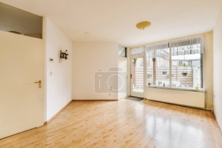 Photo for An empty living room with wood flooring and large sliding glass door leading out to the balcony area in this apartment - Royalty Free Image