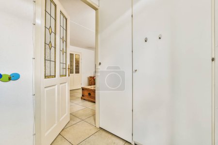 Photo for An empty hallway with white walls and tile flooring on the right side, there is a blue ball hanging in the doorway - Royalty Free Image