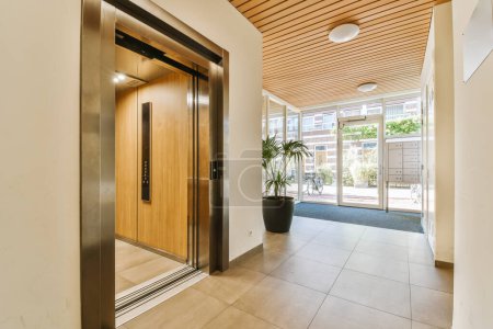 Photo for An entry way with wooden ceilinging and glass doors leading to the entrance area in this modern, light - filled home - Royalty Free Image