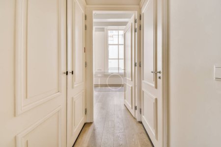 Photo for A long hallway with white walls and wood flooring on either side by side, leading to the other rooms - Royalty Free Image