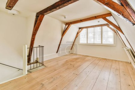 an attic style room with wood flooring and exposed beams on the ceiling in this house is very well furnished