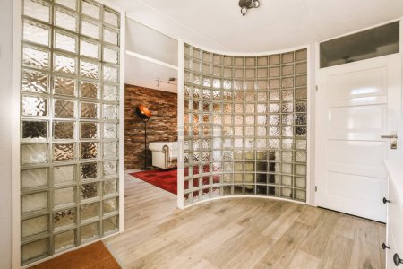 Foto de Una sala de estar con suelos de madera y tabiques de vidrio en la pared para que parezca un espejo - Imagen libre de derechos