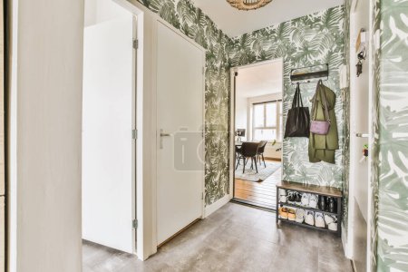 Foto de Un pasillo con papel pintado verde y blanco en las paredes, una entrada que conduce a otra habitación está en el fondo - Imagen libre de derechos