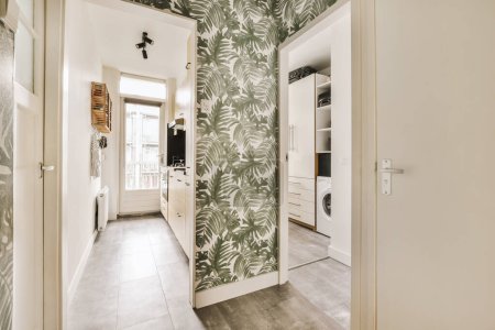 Foto de Una habitación con un patrón empapelado en las paredes, y una puerta abierta que conduce a una lavadora - Imagen libre de derechos