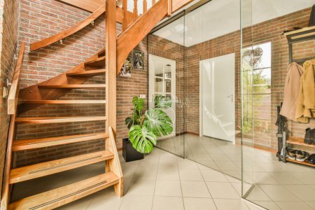 a room with a brick wall and wooden staircase leading up to the second floor, which is covered in glass