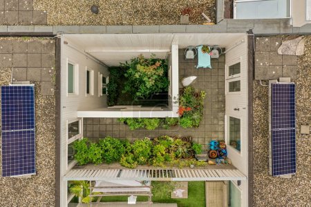 Téléchargez les photos : Une vue aérienne d'une maison avec des panneaux solaires sur le toit et quelques plantes poussant dans les vitres - en image libre de droit