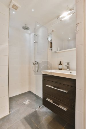 a modern bathroom with white tiles and dark wood cabinet under the sink is in front of the shower stall door