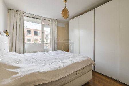 Foto de Un dormitorio con una cama y armarios empotrados en la pared, frente a una puerta corredera que conduce a un balcón - Imagen libre de derechos