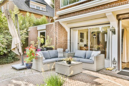 a patio with couches, tables and umbrellas on the side of the house there is an outdoor living area