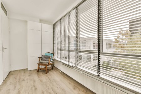 una habitación con suelos de madera y persianas blancas en las ventanas que dan a un paisaje urbano exterior