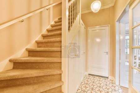 Photo for A hallway with carpet and white door handle on the left handrails are in front of the stairs, leading up to the - Royalty Free Image