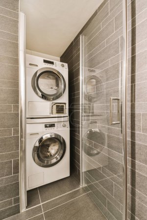Photo for A laundry room with a washer and dryer next to the shower stall in front of the washing machine - Royalty Free Image