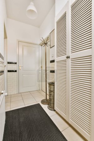 a white bathroom with black and white stripes on the shower door, toiletries, and towel rack in it